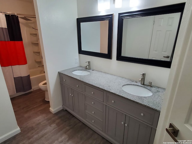 full bathroom with double sink vanity, toilet, shower / bath combo with shower curtain, and hardwood / wood-style flooring