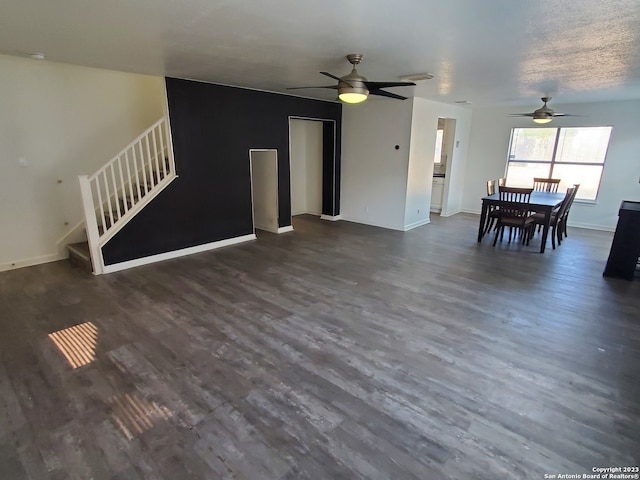 unfurnished living room with ceiling fan and dark wood-type flooring