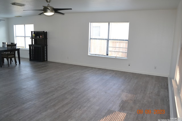 unfurnished living room featuring a healthy amount of sunlight, ceiling fan, and dark hardwood / wood-style floors