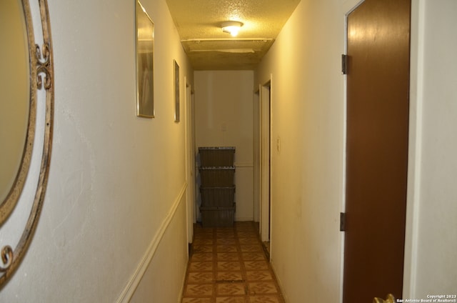 hallway with a textured ceiling and light tile flooring