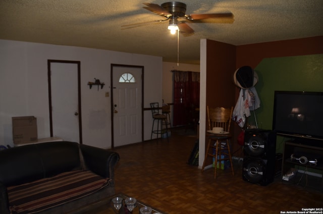 living room featuring a textured ceiling, dark parquet flooring, and ceiling fan