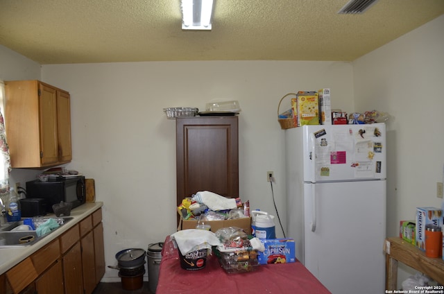 kitchen featuring sink, white refrigerator, and a textured ceiling