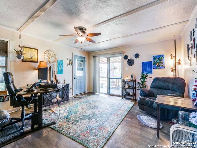 living room featuring a textured ceiling, ceiling fan, and dark wood-type flooring