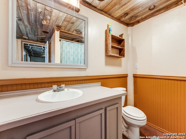 bathroom with wood ceiling, large vanity, and toilet