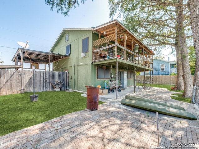 back of property with a lawn, a patio, and a wooden deck