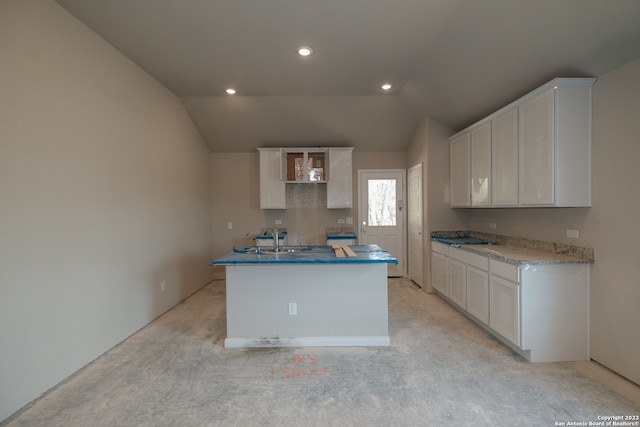 kitchen with an island with sink, lofted ceiling, sink, and white cabinets