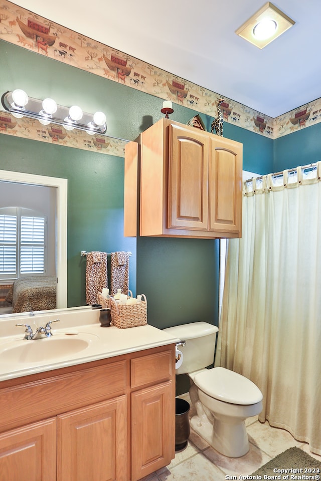 bathroom with toilet, large vanity, and tile flooring