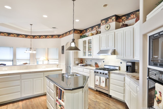 kitchen with a center island with sink, black appliances, sink, and light hardwood / wood-style flooring