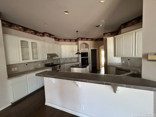 kitchen with a kitchen breakfast bar, hanging light fixtures, white cabinets, backsplash, and stainless steel appliances