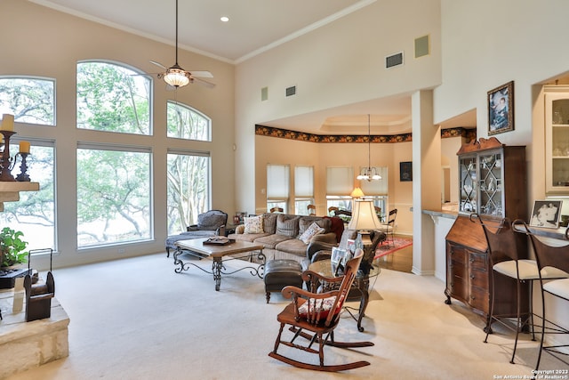 living room featuring a high ceiling, light carpet, ceiling fan with notable chandelier, and ornamental molding