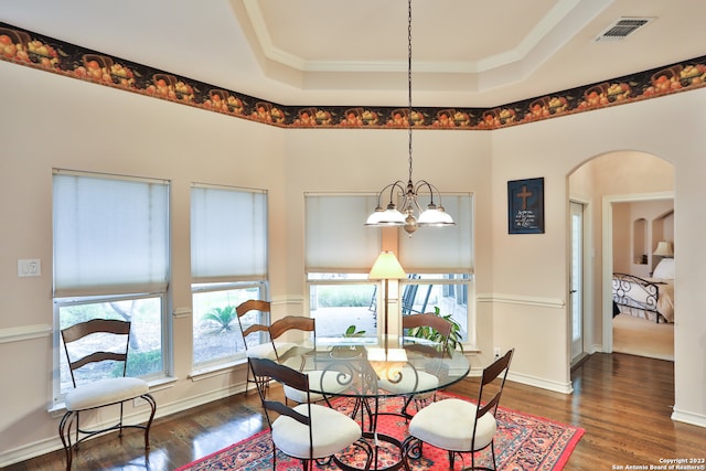 dining space with a raised ceiling, an inviting chandelier, dark wood-type flooring, and a wealth of natural light