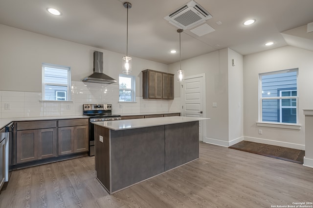 kitchen featuring electric range, wall chimney exhaust hood, hanging light fixtures, and hardwood / wood-style flooring