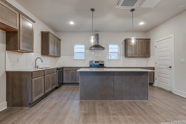 kitchen with decorative light fixtures, stainless steel range with electric cooktop, light hardwood / wood-style floors, and wall chimney range hood