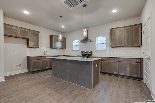 kitchen featuring wall chimney exhaust hood, sink, pendant lighting, light hardwood / wood-style flooring, and stainless steel electric range