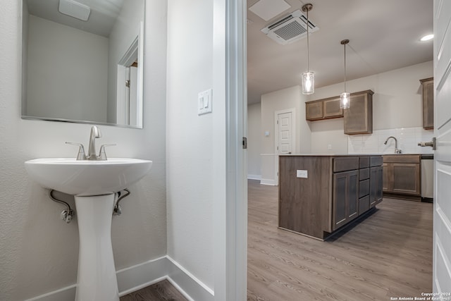 kitchen with pendant lighting, light hardwood / wood-style floors, sink, and tasteful backsplash