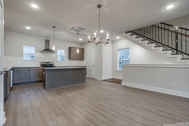 kitchen with wall chimney exhaust hood, a healthy amount of sunlight, and decorative light fixtures