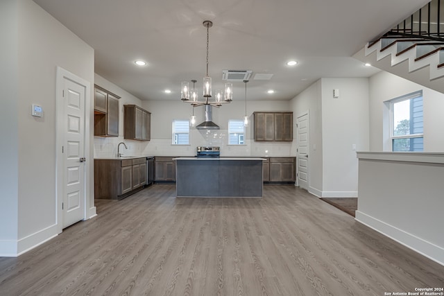 kitchen featuring a center island, stainless steel appliances, light hardwood / wood-style flooring, and wall chimney exhaust hood