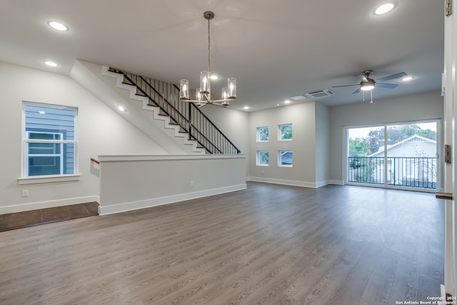 unfurnished living room featuring ceiling fan with notable chandelier and hardwood / wood-style flooring