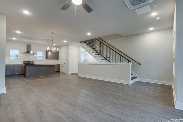 unfurnished living room with hardwood / wood-style floors, plenty of natural light, and ceiling fan with notable chandelier