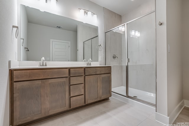 bathroom featuring tile patterned floors, a shower with door, and vanity