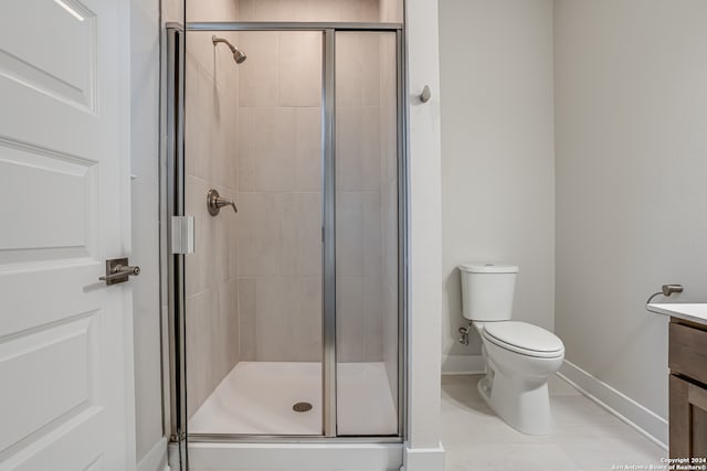 bathroom with tile patterned flooring, vanity, an enclosed shower, and toilet