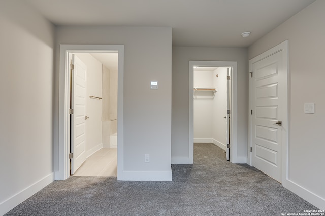 unfurnished bedroom featuring a spacious closet, light carpet, connected bathroom, and a closet