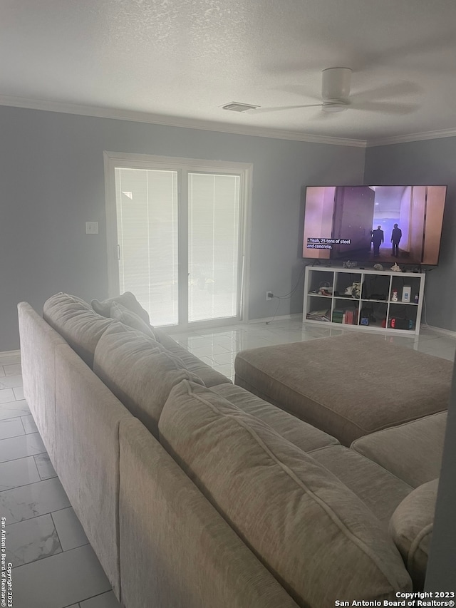 living room with ceiling fan, ornamental molding, and a textured ceiling