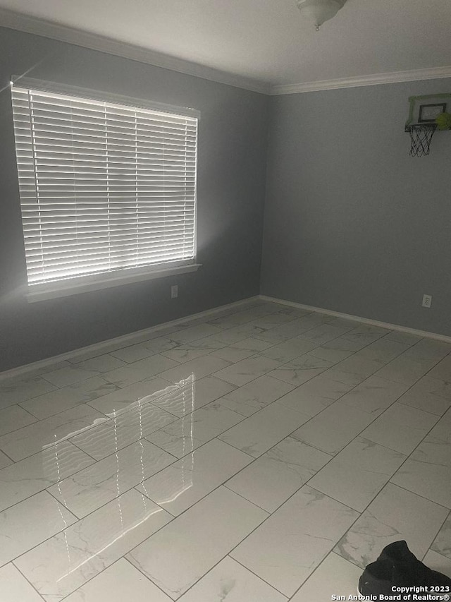 spare room featuring light tile floors and crown molding