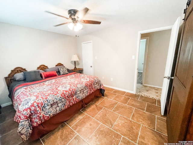 tiled bedroom featuring a barn door and ceiling fan