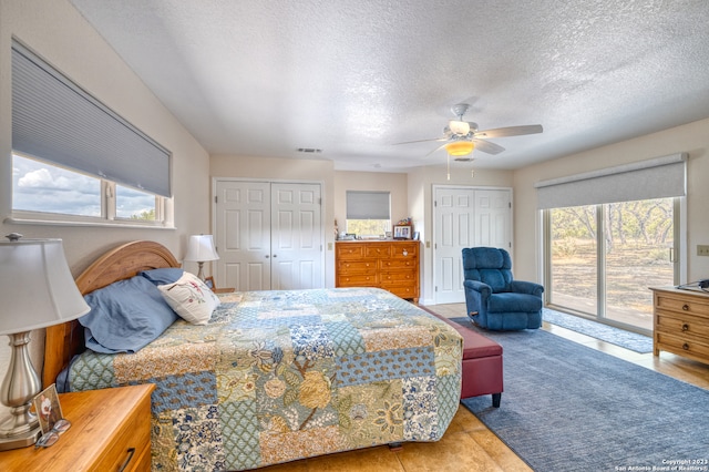 bedroom with a textured ceiling, access to exterior, ceiling fan, and multiple windows