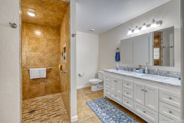 bathroom featuring tiled shower, a textured ceiling, tile flooring, toilet, and double vanity