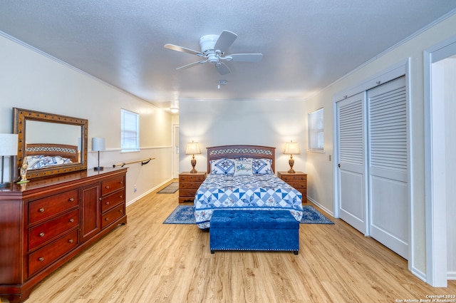 bedroom with ceiling fan, crown molding, a textured ceiling, a closet, and light wood-type flooring