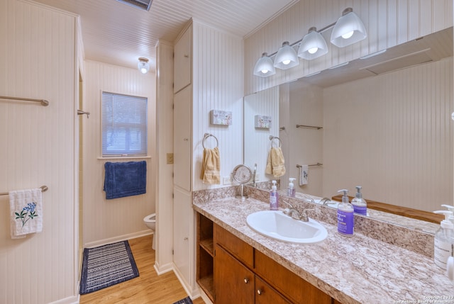 bathroom featuring oversized vanity, toilet, and wood-type flooring