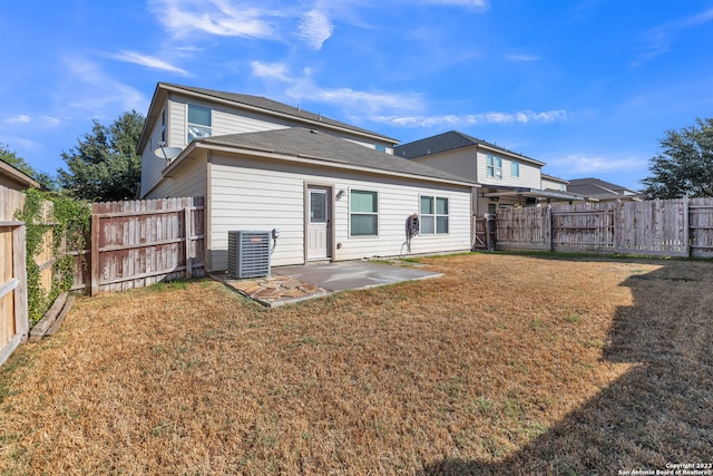 rear view of house with central AC unit, a patio, and a yard