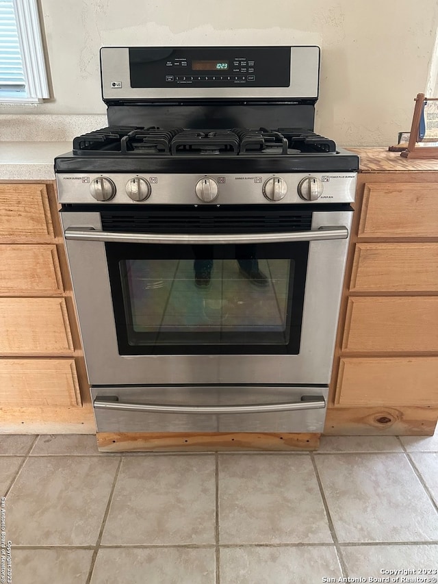 room details featuring gas stove and light tile flooring