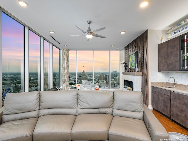 living room featuring expansive windows, sink, ceiling fan, and light hardwood / wood-style flooring