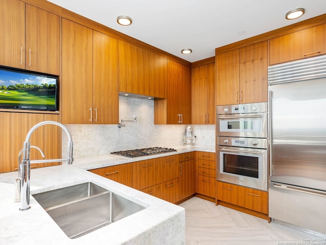 kitchen featuring appliances with stainless steel finishes, light stone countertops, backsplash, and sink