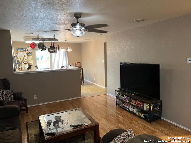 living room featuring light hardwood / wood-style floors, a textured ceiling, and ceiling fan with notable chandelier