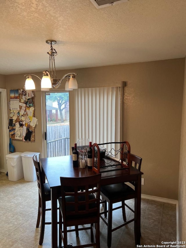 tiled dining space with a notable chandelier and a textured ceiling