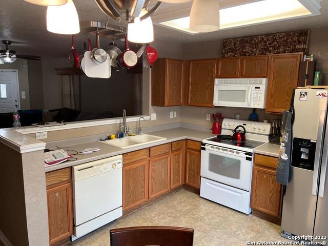 kitchen featuring light tile flooring, ceiling fan, white appliances, and sink