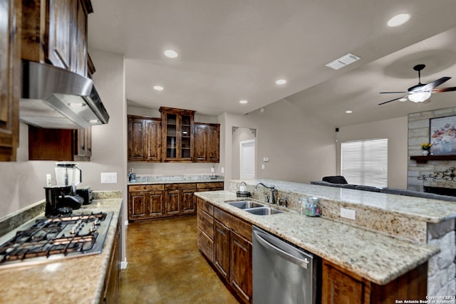 kitchen with light stone countertops, ceiling fan, appliances with stainless steel finishes, sink, and a center island with sink