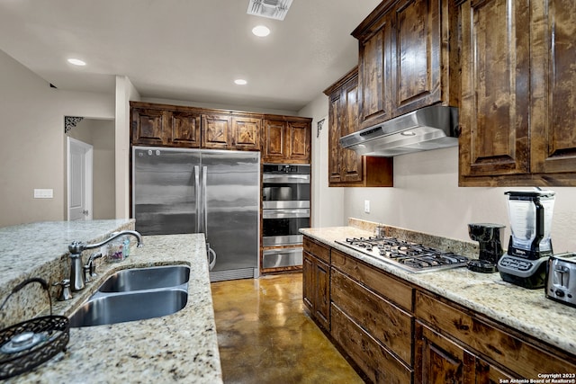 kitchen featuring range hood, appliances with stainless steel finishes, dark brown cabinetry, light stone countertops, and sink