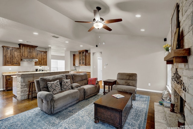 living room featuring a stone fireplace, ceiling fan, and high vaulted ceiling