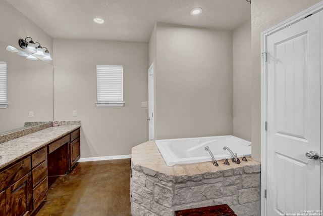 bathroom featuring concrete floors, tiled tub, and oversized vanity