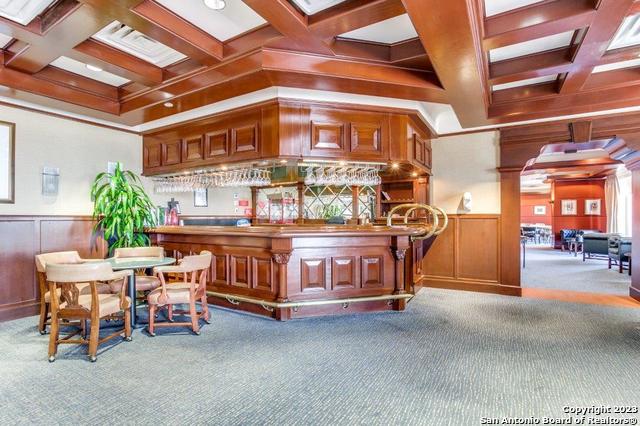 misc room featuring light colored carpet, wooden walls, and ornate columns