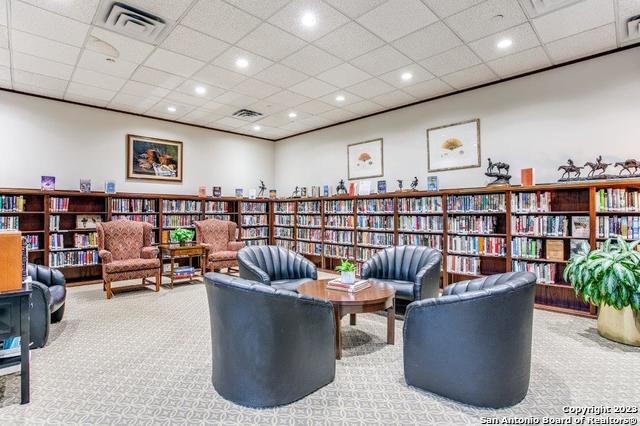 living area with a paneled ceiling and light carpet