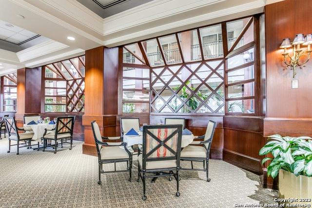 carpeted dining area with ornamental molding and wooden walls