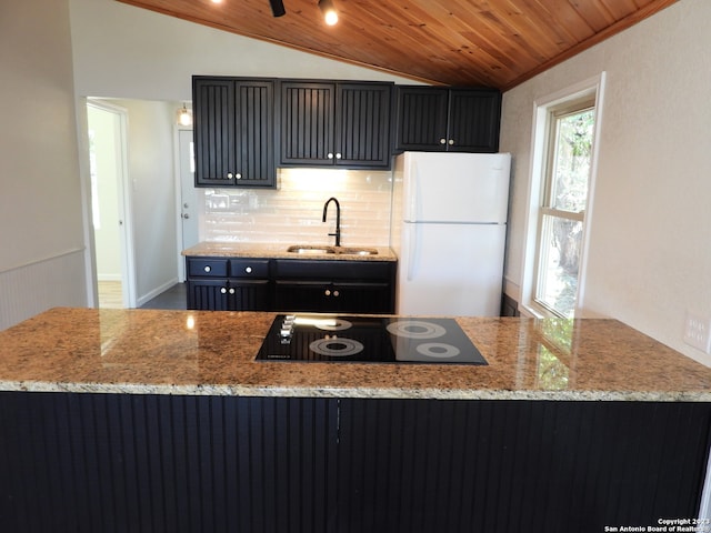 kitchen with wooden ceiling, black electric cooktop, a sink, vaulted ceiling, and freestanding refrigerator