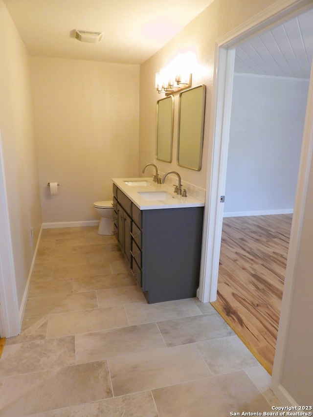 bathroom with double vanity, a sink, toilet, and baseboards