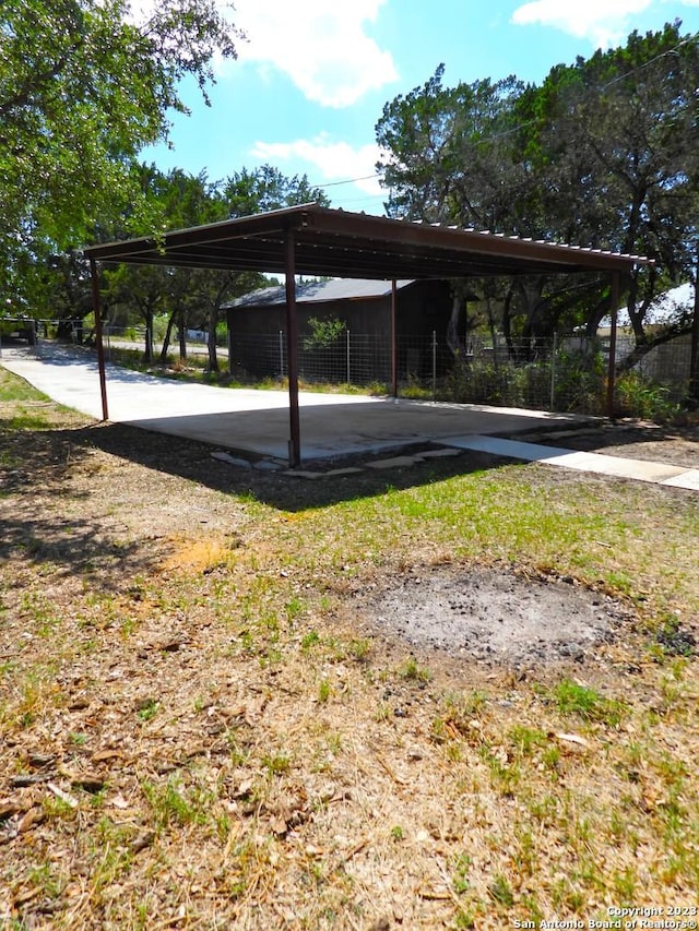 view of parking / parking lot with fence and a detached carport